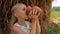 Pretty blond girl drinks fresh cow`s milk from a clay jug against haystack in summer on farm.