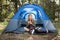 Pretty blonde camper smiling and sitting in tent