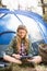 Pretty blonde camper using tablet and sitting in tent