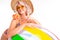 Pretty blonde caucasian female stands in swimsuit with big rubber beach colourful ball, lolipop and smiles isolated on