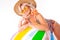 Pretty blonde caucasian female stands in swimsuit with big rubber beach colourful ball, lolipop and smiles isolated on