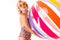 Pretty blonde caucasian female stands in swimsuit with big rubber beach colourful ball and smiles isolated on white