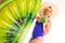 Pretty blonde caucasian female stands in swimsuit with rubber beach kiwi mattress and drinks juice  on white