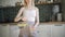 Pretty blonde drinks lemon water. Young woman pours water with lemon into a glass and drinks in the kitchen.