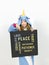 Pretty blonde girl with cozy blue unicorn costume with blackboard with different words on it like love and peace and some more