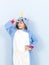 Pretty blonde girl with cozy blue unicorn costume is posing in the studio in front of blue wall and is happy