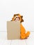 Pretty blonde girl with cozy lion costume is holding a brown sign in the studio in front of white wall