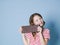 Pretty blonde girl with a giant bar of chocolate is posing in front of blue background and is happy smiling