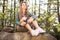 Pretty blonde hiker with binoculars sitting on stone