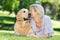 Pretty blonde kissing her dog in the park