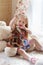 Pretty blonde little girl sits on carpet near window