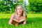 Pretty blonde lying on the grass and holds thick book