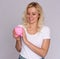 Pretty blonde woman with freckles holds a piggy bank