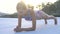 Pretty blonde woman wearing colourful bikini doing plank push up exercise on a rooftop during sunrise