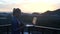 Pretty blonde woman working on a laptop while standing on a rooftop over beautiful sunrise