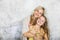 Pretty, blonde young mother poses and cuddles with her daughter in front of a concrete wall and having a lot of fun