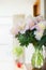 Pretty Bouquet of pink pale peonies in a glass jug with water on the table against the background of a bright room. Home