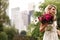 Pretty bride holds rich dark pink bouquet of peonies in her arm