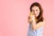 A pretty brunette holds a banana like a gun on a pink background. Selective focus