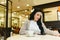 Pretty brunette woman checking her smartphone while having breakfast drinking coffee in a retro restaurant