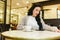 Pretty brunette woman checking her smartphone while having breakfast drinking coffee in a retro restaurant