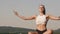 Pretty brunette woman in sporrtswear practicing yoga on the rock. Green mountain background