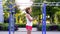 Pretty brunette woman train her biceps muscles with dumbbells at warm summer day at the park