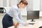 Pretty business woman in glasses in the office at the working table by the window signs documents