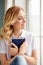 Pretty calm cute woman looking in window and holding book