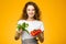 Pretty caucasian girl with curly hair holding vegetables