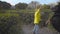 Pretty Caucasian girl in mustard hat and yellow coat raising hand up and her dog standing on hind legs. Child playing