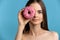 Pretty caucasian model girl hide her eye with pink glaze donuts. Temptation food. Isolated on blue background