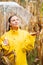 Pretty caucasian young girl in yellow raincoat standing in corn field with transparent umbrella. Woman checks if it is