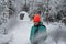 A pretty caucasian young woman in a winter wonderland enjoying the snow fashion photoshoot wearing colourful jacket and red cap