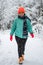 A pretty caucasian young woman in a winter wonderland enjoying the snow fashion walk wearing colourful jacket and red cap