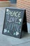 Pretty chalk board sign advertising thoughts on peace, love, and shopping, set outside doorway of retail shop