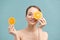 Pretty charming joyful attractive cheerful funny comic positive nude natural pure girl having two pieces of orange, closing one