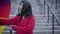 Pretty cheerful Caucasian woman folding umbrella and looking at camera. Joyful lady in red coat enjoying light rain