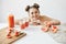 Pretty cheerful girl with buns smiling looking at camera sitting at table with slices of grapefruit healthy detox diet