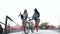 Pretty cheerful young ladies in fashion clothes walking with bicycle and skateboard on the glass observation deck