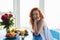 Pretty cheerful young redhead lady near flowers and fruits