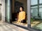 Pretty Chinese young woman meditating at home, sitting on floor with furry cushion in sun light, exercise, Lotus pose, prayer