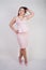 Pretty chubby positive girl dancing in pink fashionable dress on white studio background