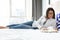 Pretty concentrated young woman reading a book while lying on bed in hotel room