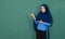 A pretty confident Asian Muslim woman dressed nicely wearing blue hijab posing for photographing acting introducing something in a