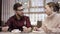 Pretty couple is waiting for meal by table in restaurant holding forks and knives