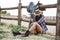 Pretty cowgirl resting while leaning on the ranch fence