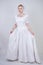 Pretty curvy adult woman with short hair wearing long vintage wedding dress with sun style skirt. young caucasian bride with veil