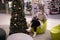 Pretty customer in mask, cozy white winter coat and high boots is sitting relaxed in armchair in shopping center