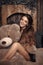 Pretty cute brunette girl posing with big teddy bear on the floor in cozy comfortable interior home.